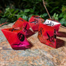 Red and clear dice with black symbols on a stone surface with greenery in the background